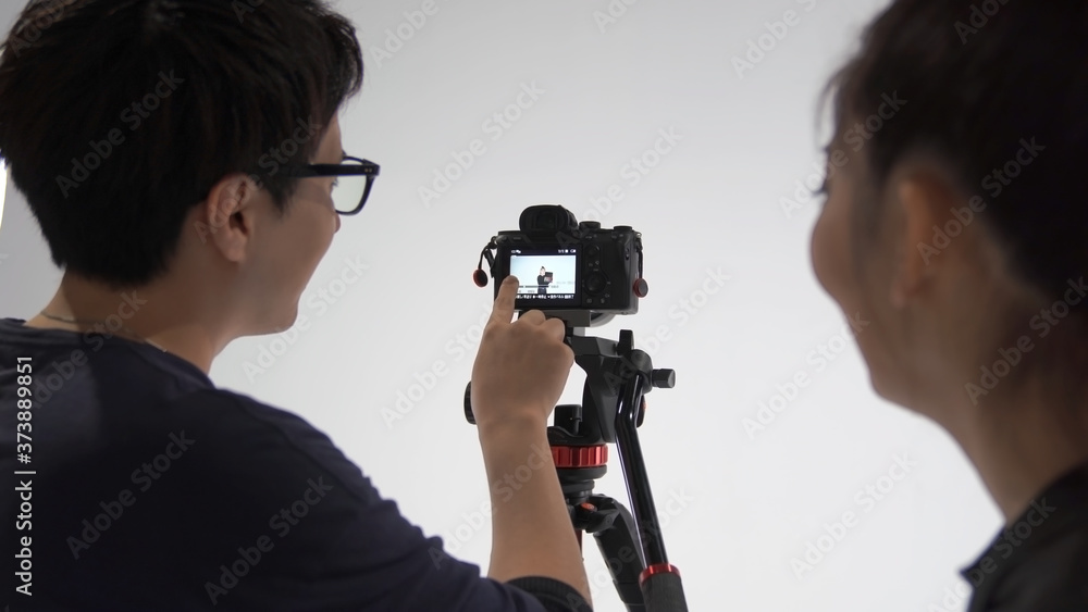 Obraz premium 撮った動画を確認する映像カメラマンと被写体の女性