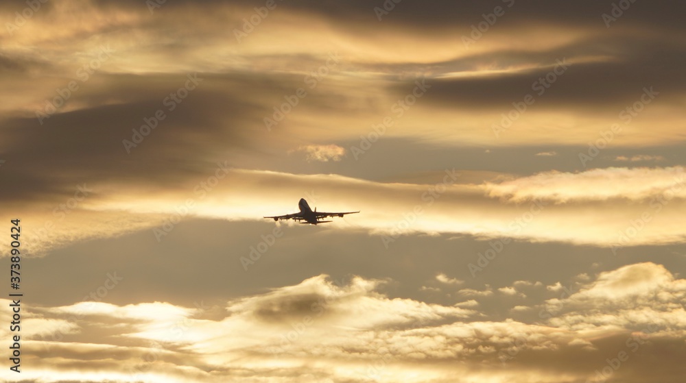 an airplane flying through the clouds at sunrise    
