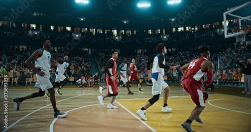 Basketball player scores a goal on a professional basketball stadium. Stadium is made in 3d with animated crowd. Dynamic shot. photo