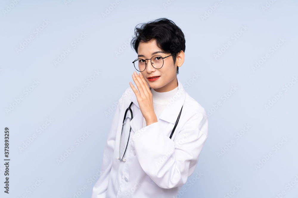 Doctor Asian woman over isolated blue background whispering something Doctor Asian woman over isolated blue background whispering something