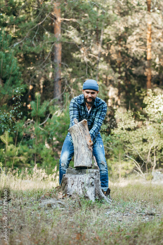 Stylish bearded forester chopping wood with an axe