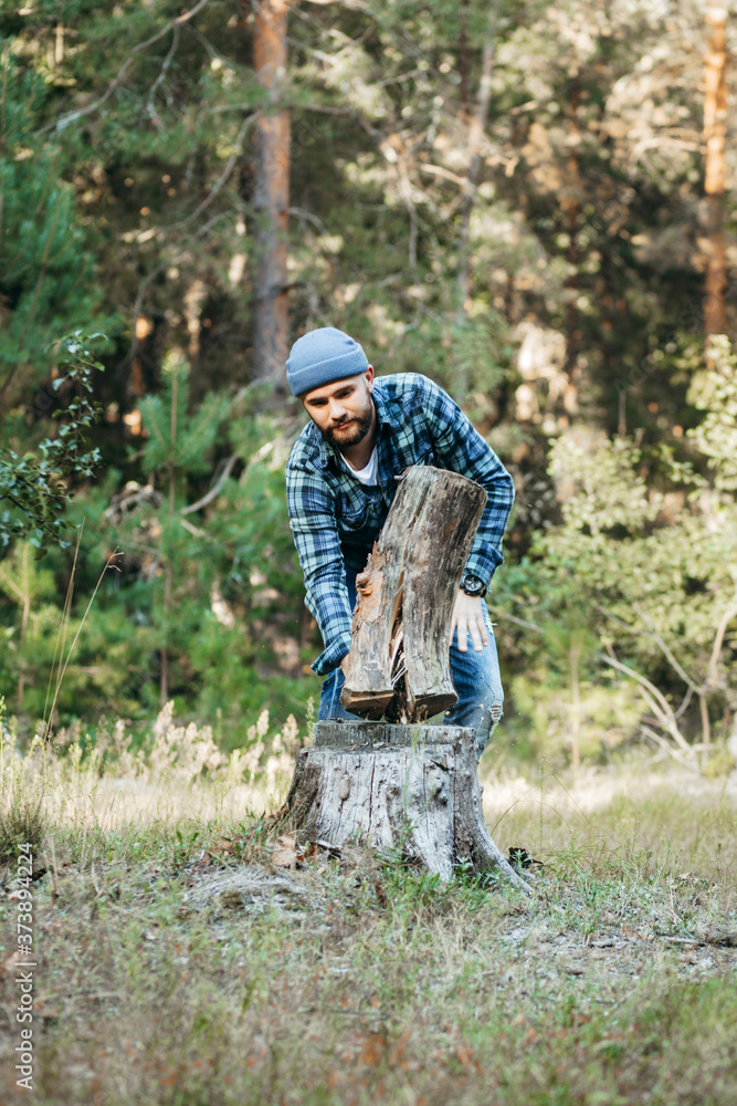 Stylish bearded forester chopping wood with an axe