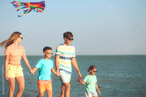 Happy family flying kite on sea beach at resort