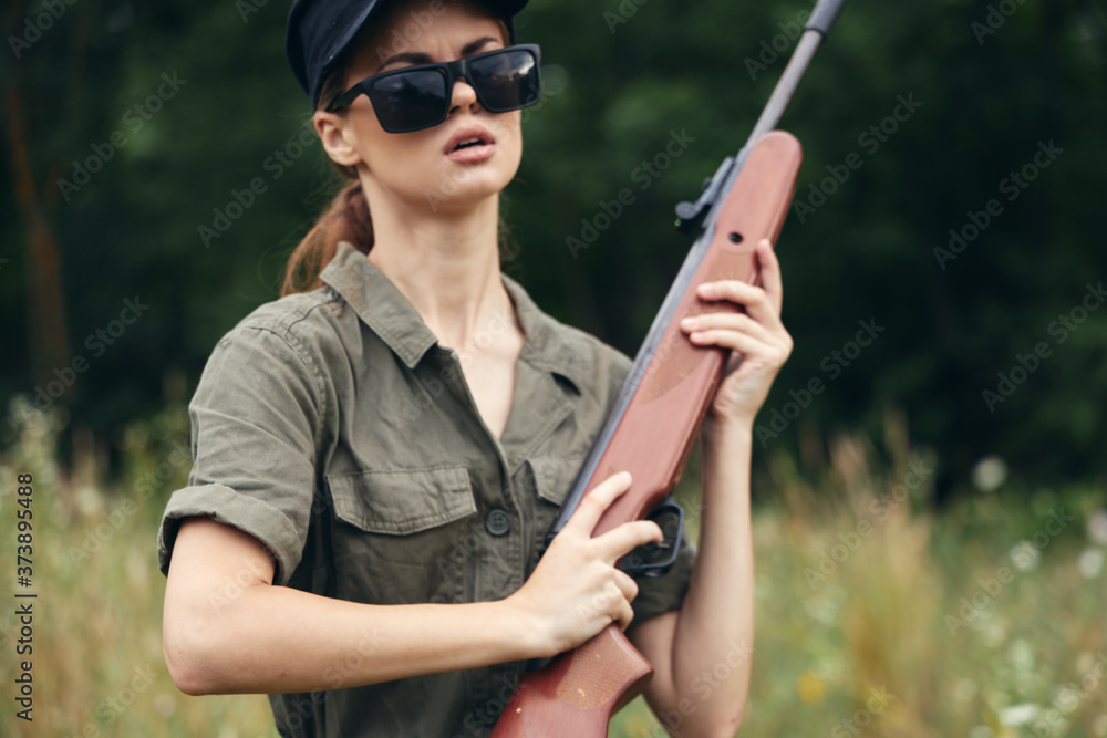 Fototapeta premium Woman on outdoor Hunting with a weapon in his hands green leaves 