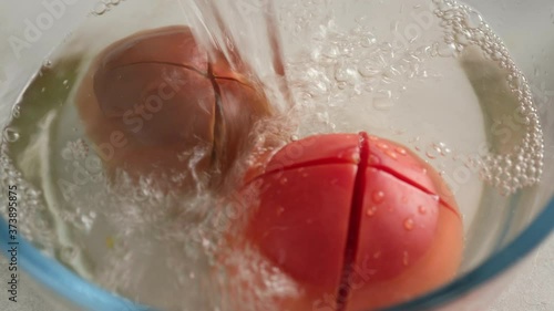 The cook blanch tomatoes with hot water. Pouring boiled hot water over a tomato. Cooking vegetarian food, cooking food in the kitchen. photo