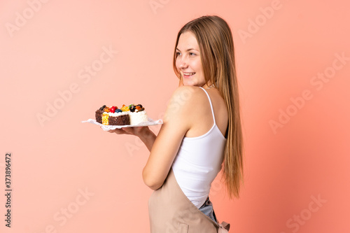 Pastry Ukrainian chef holding a muffins isolated on pink background looking to the side