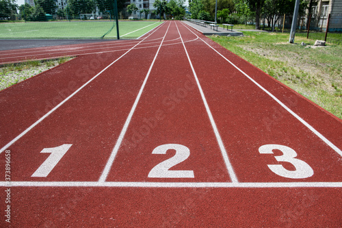 Nice red race track with white starting line with numbers at stadium 