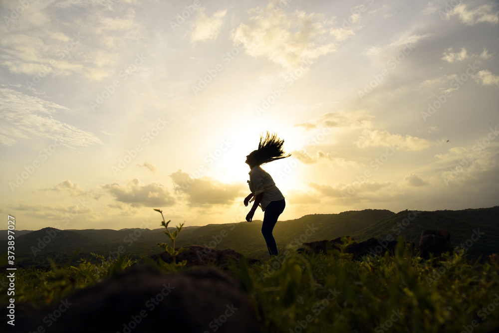 Silhouette of a woman waving her hair at sunset.