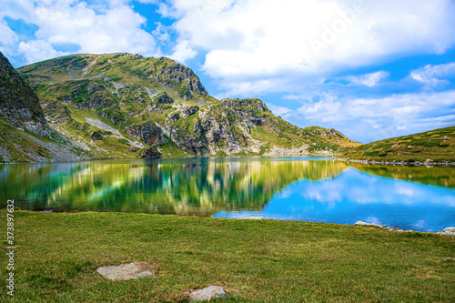 Fototapeta Naklejka Na Ścianę i Meble -  National park  Seven Rila Lakes in Bulgarian mountains.  Hiking in Bulgaria, Europe. Blue lake, purple flowers and high mount peak in summer.  Amazing scenery wallpaper for tourism. Beautiful nature.
