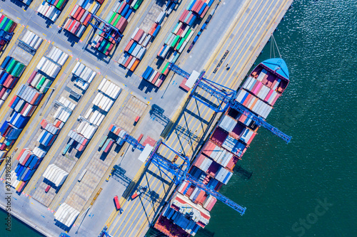 Container ship in export and import business and logistics. Shipping cargo to harbor by crane. Water transport International. Aerial view