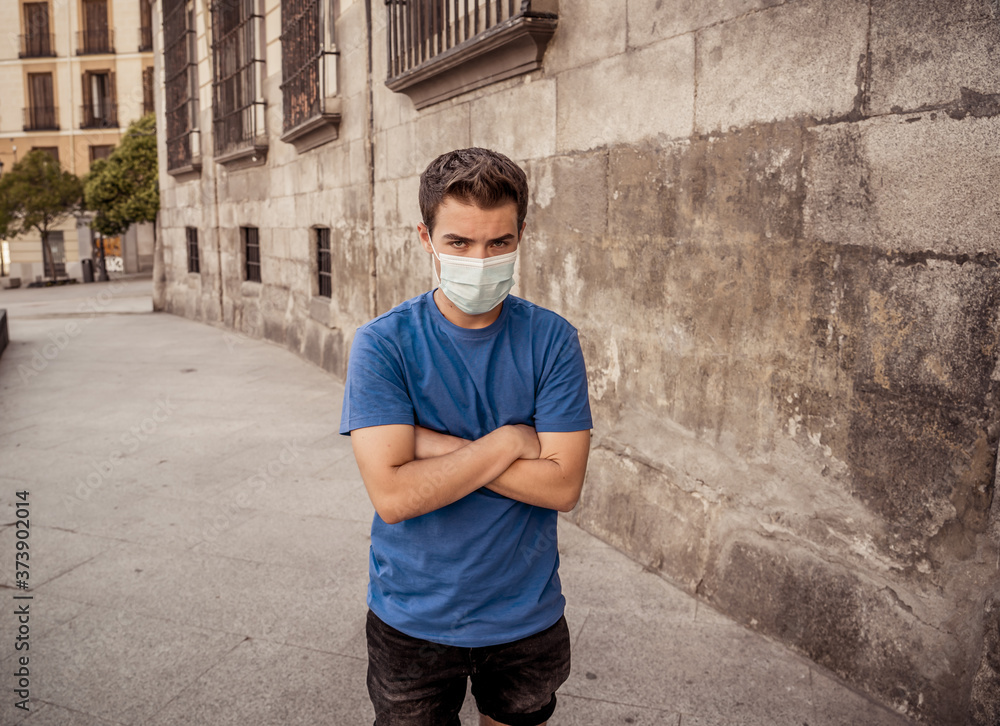 Portrait of young sad man with protective surgical face mask in public spaces in the new normal Portrait of young sad man with protective surgical face mask in public spaces in the new normal