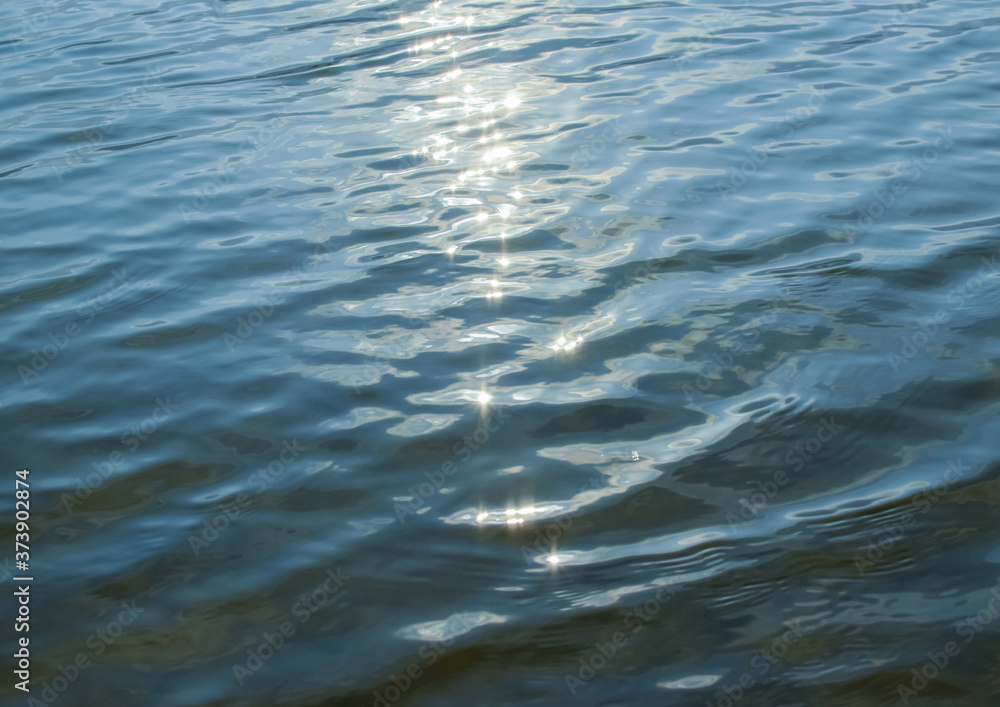 Naklejka premium Sun glare on the water. Blue water summer background. Blur.