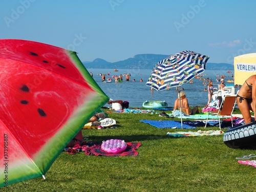 Fotografija Balatonmáriafürdő, Hungary - July 29, 2020: Colorful umbrellas, sunbathing and b