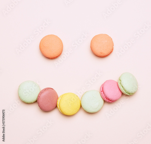 baked multi-colored macarons cookies lie in a row on a beige background