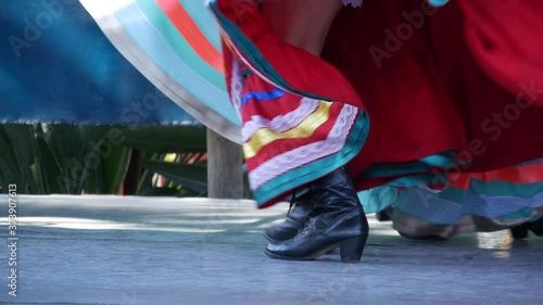 Latino women in colourful traditional dresses dancing Jarabe tapatio, mexican national folk hat dance. Street performance of female hispanic ballet in multi colored ethnic skirts. Girls in costumes.
