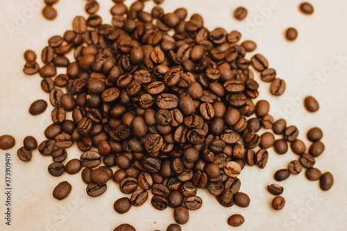 Coffee bean background. Dark-colored roasted coffee beans scattered on Kraft paper.