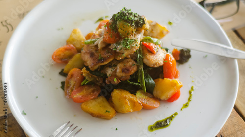 Chicken with potatoes and vegetables on a white plate in a restaurant