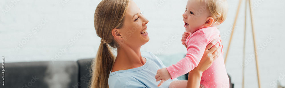 Panoramic shot of woman holding baby daughter at home Panoramic shot of woman holding baby daughter at home