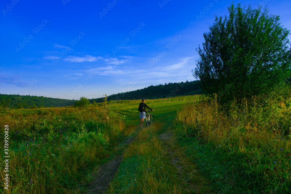 landscape of a mountain road on which a man walks with a bicycle