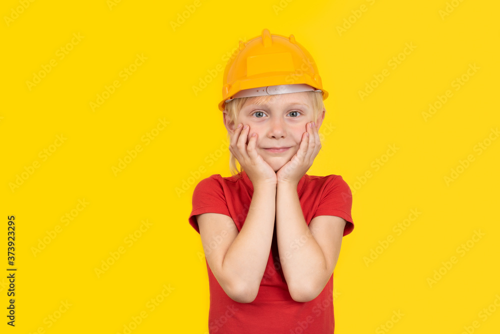 Cute fair-haired boy in protective orange helmet on yellow background. Cute fair-haired boy in protective orange helmet on yellow background.