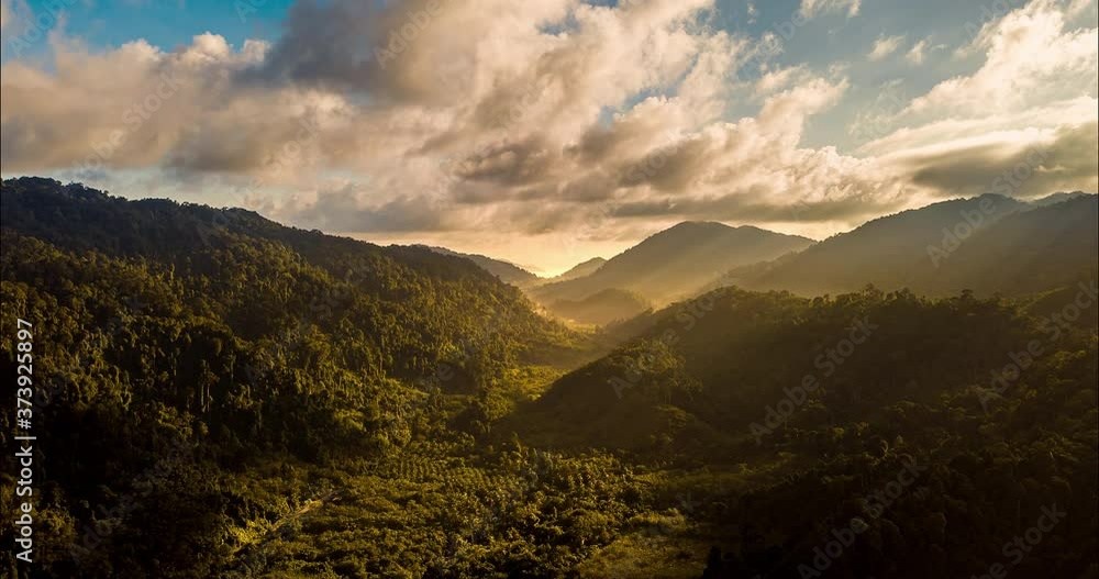 Aerial drone hyperlapse timelapse of beautiful tropical valley between mountains. The first rays of the rising sun break through the clouds and clouds. The last rays of the sunset hit the tree crowns.