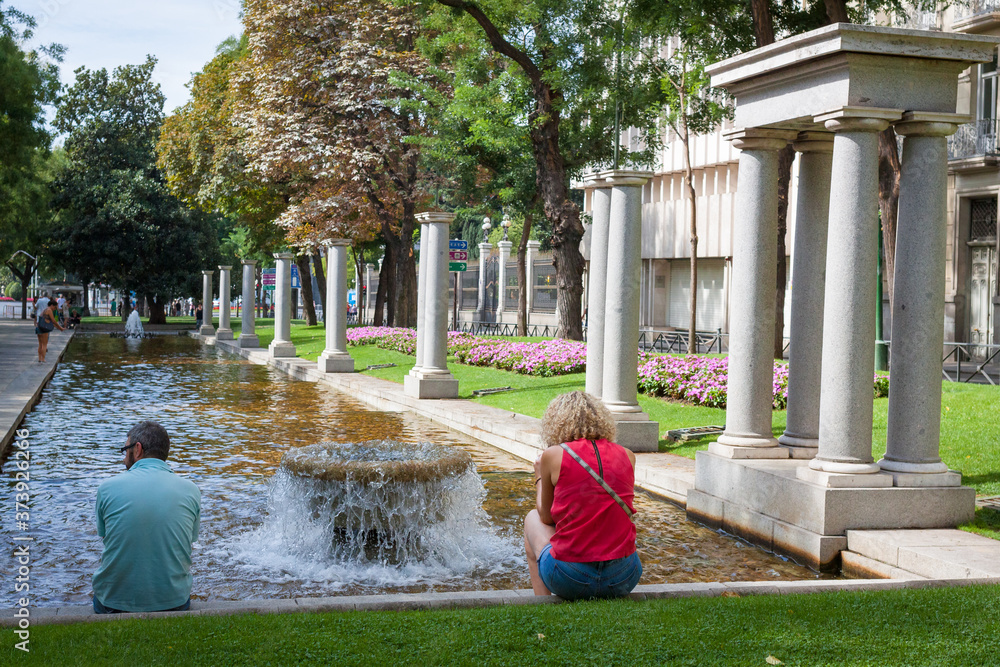 Streets with a people and fountain with a small pull in Madrid in Spain in autumn, September