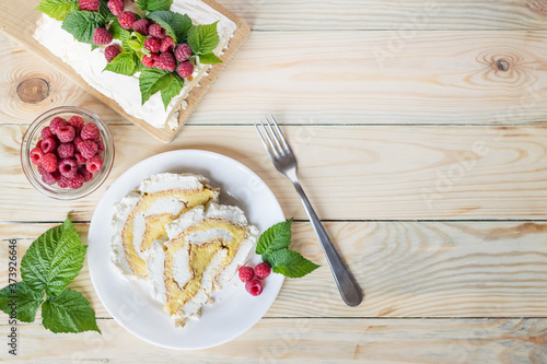 Meringue roll cake with cream and fresh raspberries. Roulade, summer dessert. Selective focus, horizontal orientation, copyspace, top view.