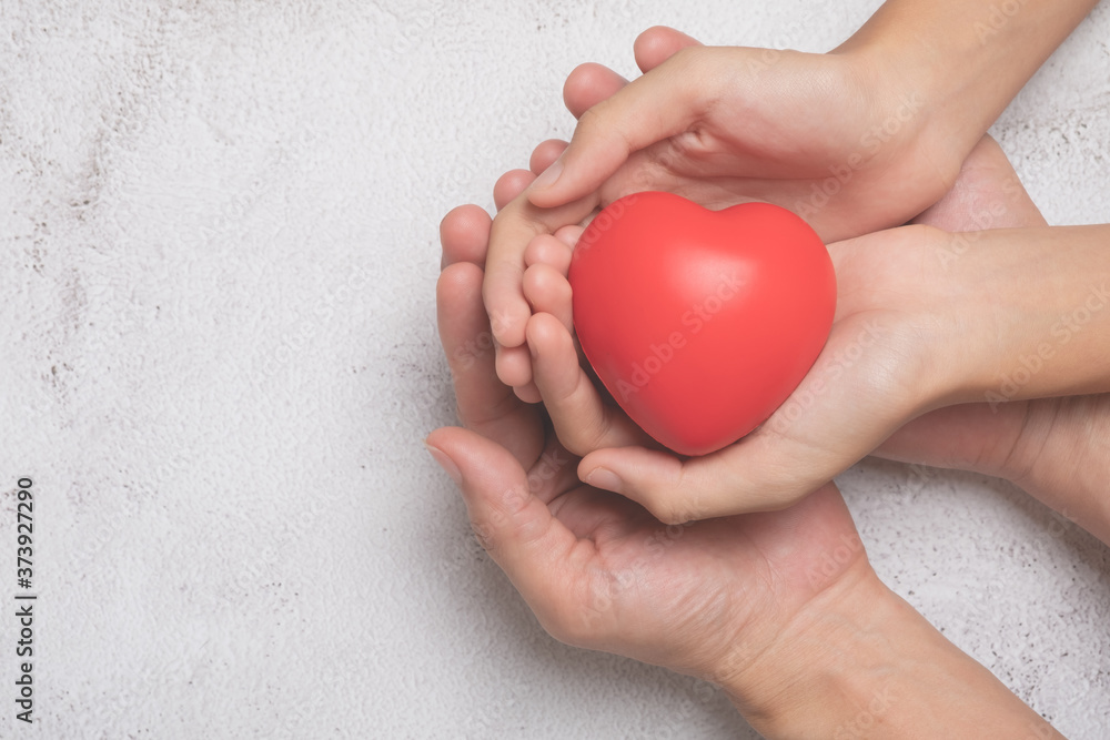 Hands holding a red heart on cement background, CSR or Corporate Social Responsibility, health care, family insurance, heart donate concept, world health day. Hands holding a red heart on cement background, CSR or Corporate Social Responsibility, health care, family insurance, heart donate concept, world health day.