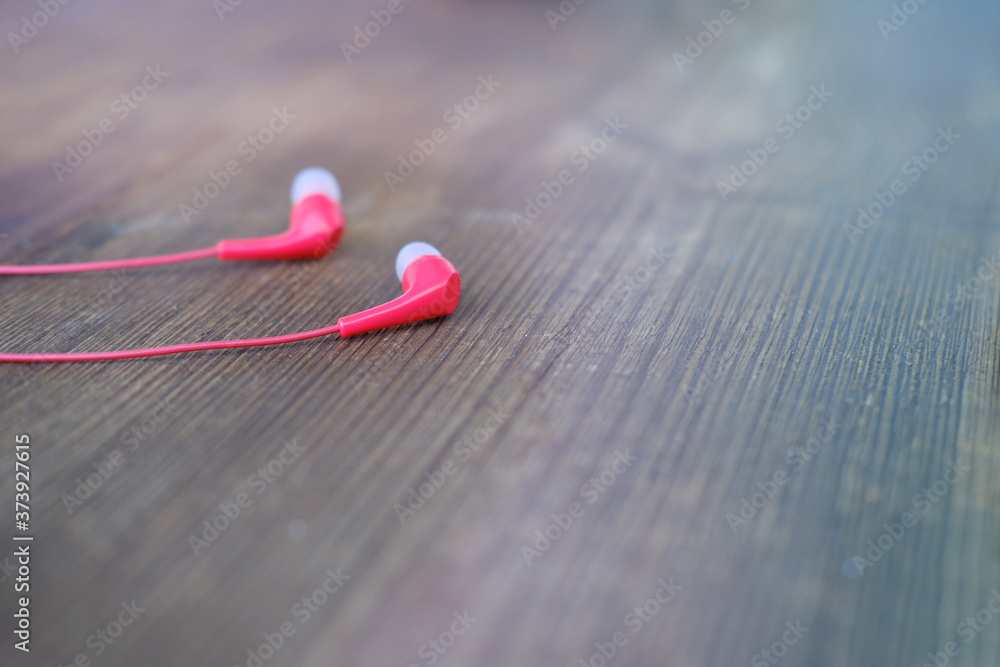 small red wired headphones lie on a vintage wooden table, blurred background, music harmony concept, inspiration, hobby, lifestyle