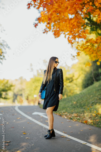 Beautiful caucasian woman walking on the road in autumn.  Yellow foliage. © eduard