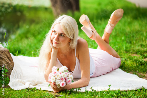 Portrait of a young blonde woman resting near a pond in a summer park © Andrey_Arkusha