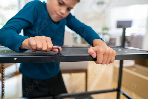 Close up view of a boy using allen wrench to assemble furniture