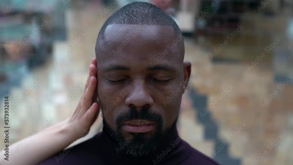 black man is standing with closed eyes and hands of white woman are stroking his head black man is standing with closed eyes and hands of white woman are stroking his head