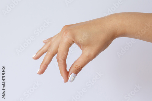 A woman's hand is holding something. Some object is hanging in the hand. Hand gesture and symbol. Sign language.
