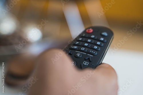 Hand holding remote control for watching tv in the living room