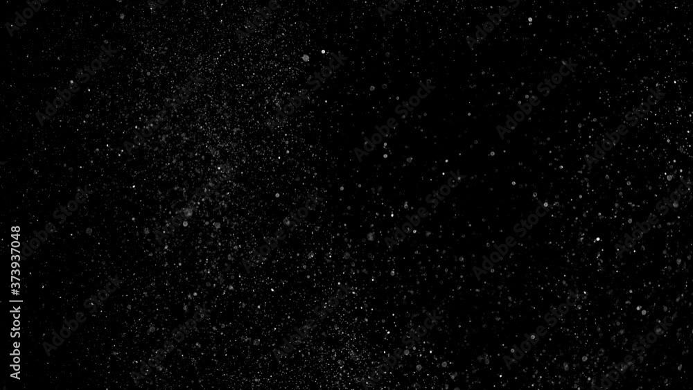 Dust particles sparkling on black background with white light bokeh effect
