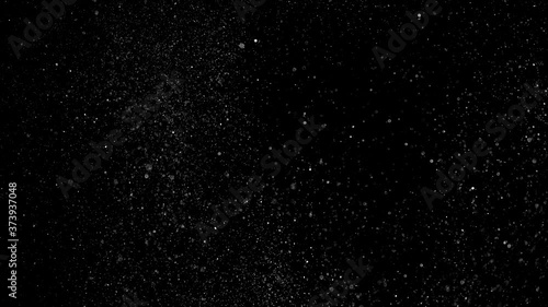 Dust particles sparkling on black background with white light bokeh effect