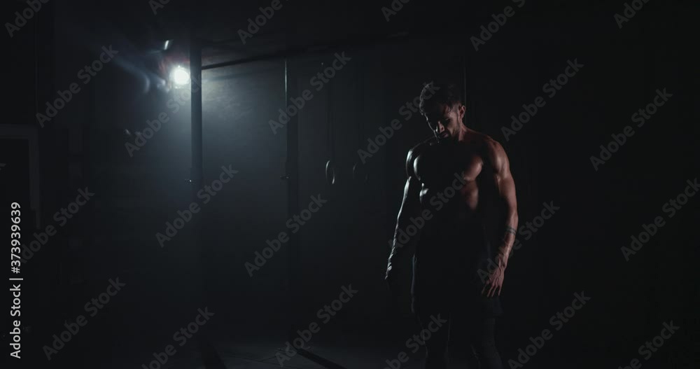 In the dark cross fitness class bodybuilding man with the sweating body in front of the camera In the dark cross fitness class bodybuilding man with the sweating body in front of the camera