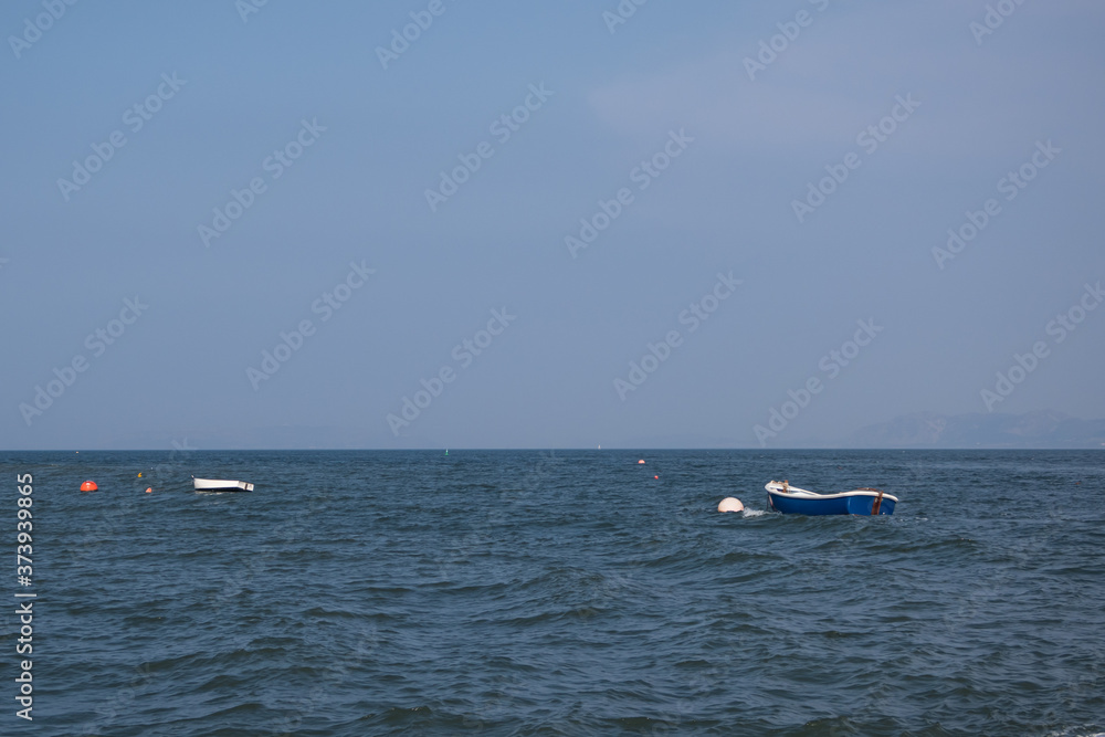 Small boats moored at sea. Blue summer sky and calm sea