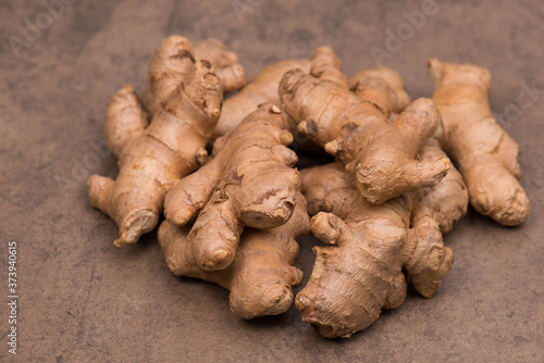 Fresh ginger roots on a brown textured background
