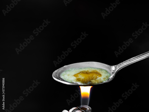 Ketamine on spoon with cigarette lighter on black background.  Dangerous drug. Addictive substance. narcotic concept.