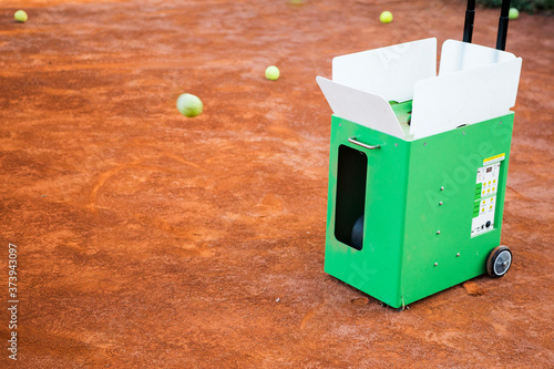 Ball machine on slag tennis court.