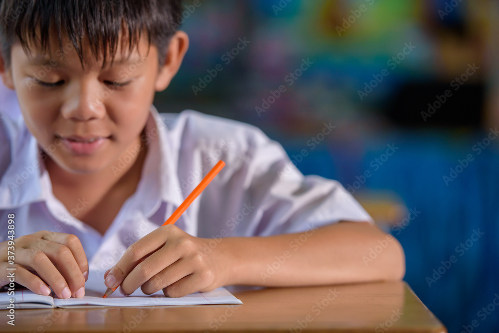 Close-up of an Asian male student in elementary school writing with her left hand. Concept: left-handed Close-up of an Asian male student in elementary school writing with her left hand. Concept: left-handed