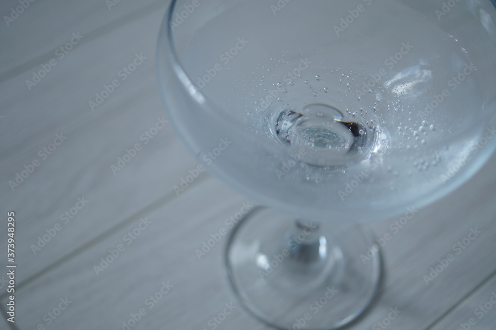 The cocktail glass stands on a light wooden plank surface. A glass in the right part of the frame, with sparkling water in it The cocktail glass stands on a light wooden plank surface. A glass in the right part of the frame, with sparkling water in it