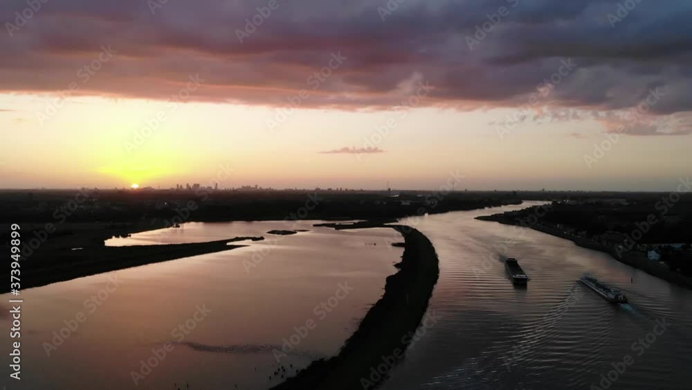 Dutch cargo vessels sailing on a dutch river during sunset. Steady drone shot Dutch cargo vessels sailing on a dutch river during sunset. Steady drone shot