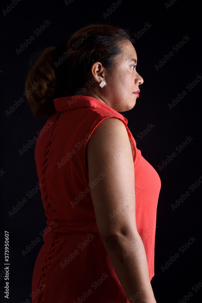 portrait of a woman standing on black background, side view