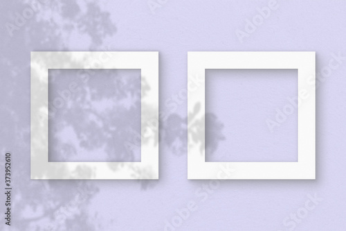 Two square sheet of white textured paper on the lilac wall background. Mockup with an overlay of plant shadows. Natural light casts shadows from the leaves of an exotic plant. Flat lay, top view