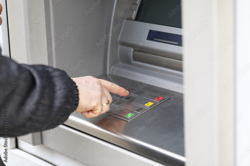 Man dials PIN code to withdraw money from ATM Man dials PIN code to withdraw money from ATM