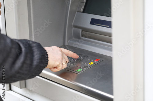 Man dials PIN code to withdraw money from ATM