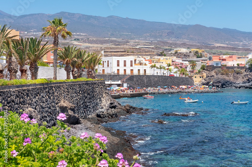 Puerto de Alcala, Tenerife, Canary Islands, Spain - June 21, 2020: lots of residents sunbathing and swimming in the small harbor in Alcala in a hot sunny summer day after the strict lockdown finished